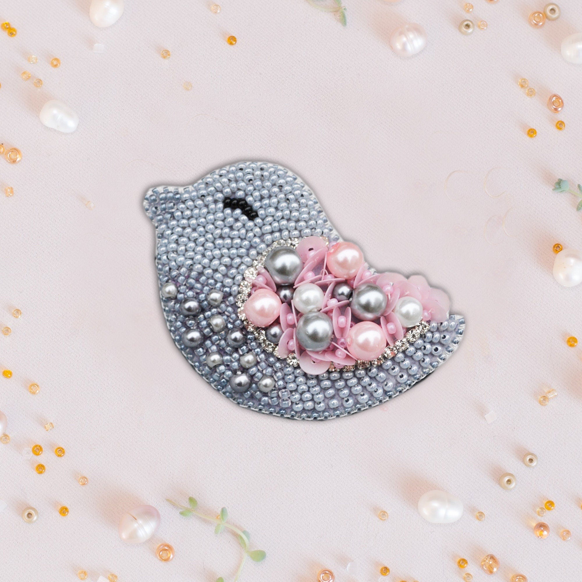 a pink and silver bird brooch with pearls
