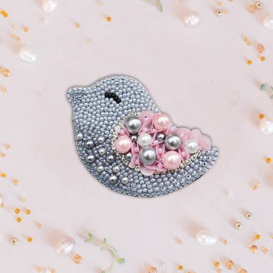 a pink and silver bird brooch with pearls