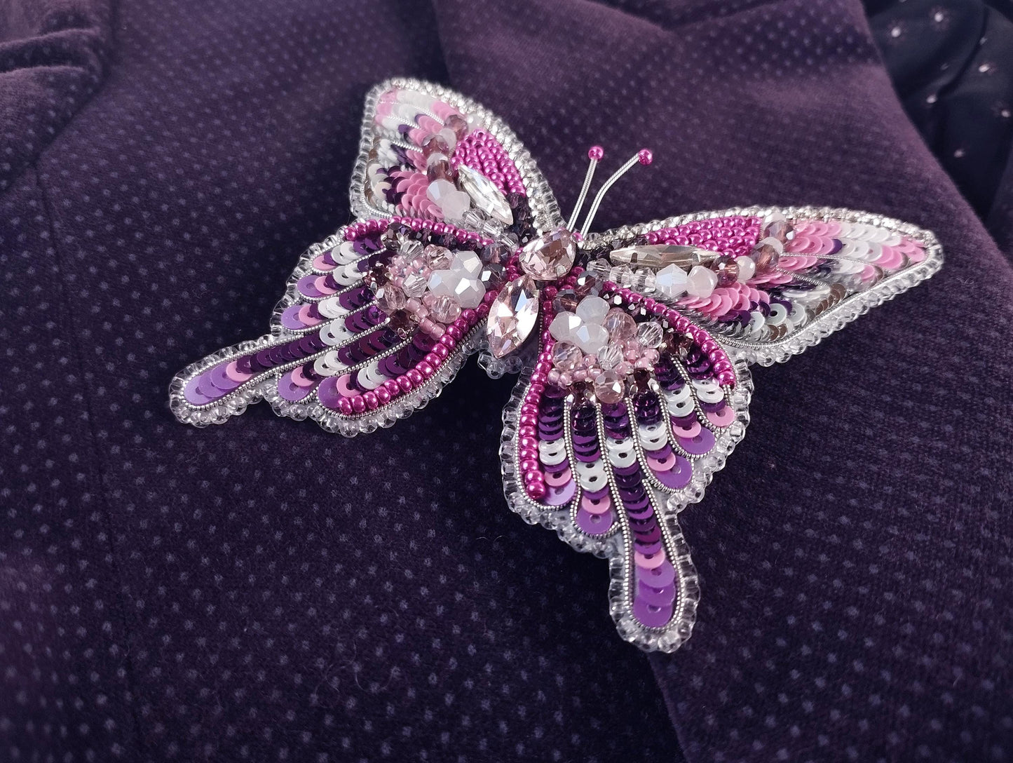 a purple butterfly brooch sitting on top of a purple cloth