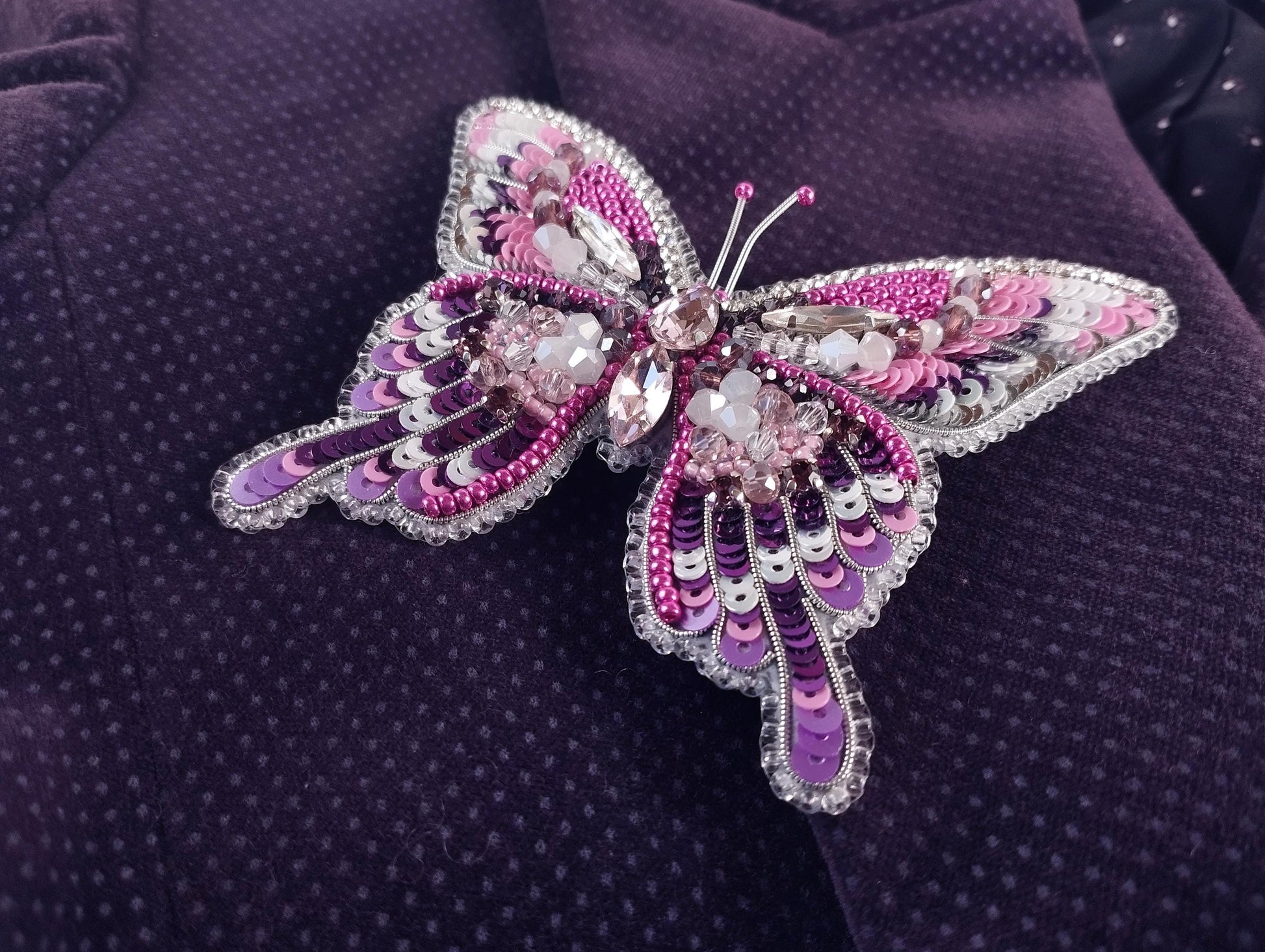 a purple butterfly brooch sitting on top of a purple cloth