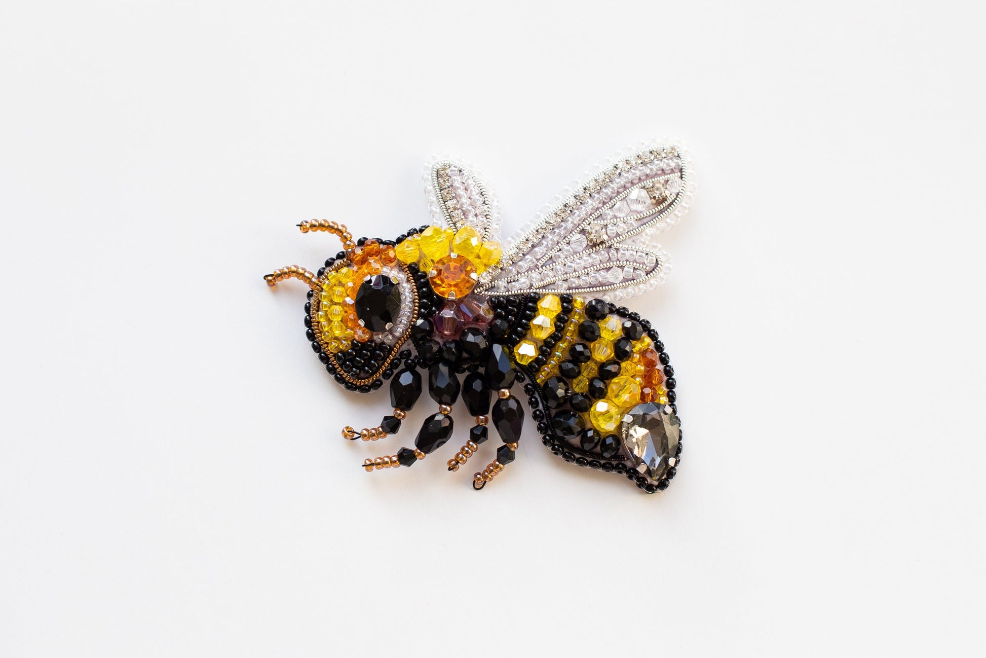 a beaded bee brooch sitting on top of a white surface