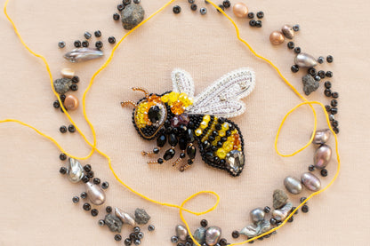 a beaded bee sitting on top of a yellow string