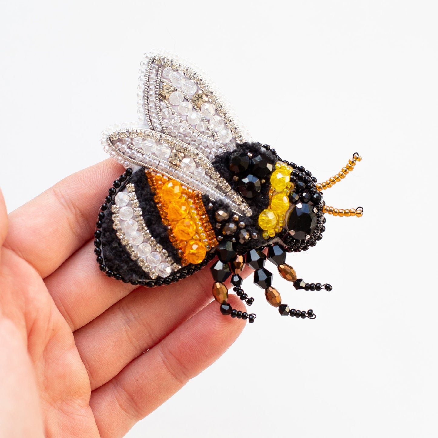 a small beaded bee sitting on top of a persons hand