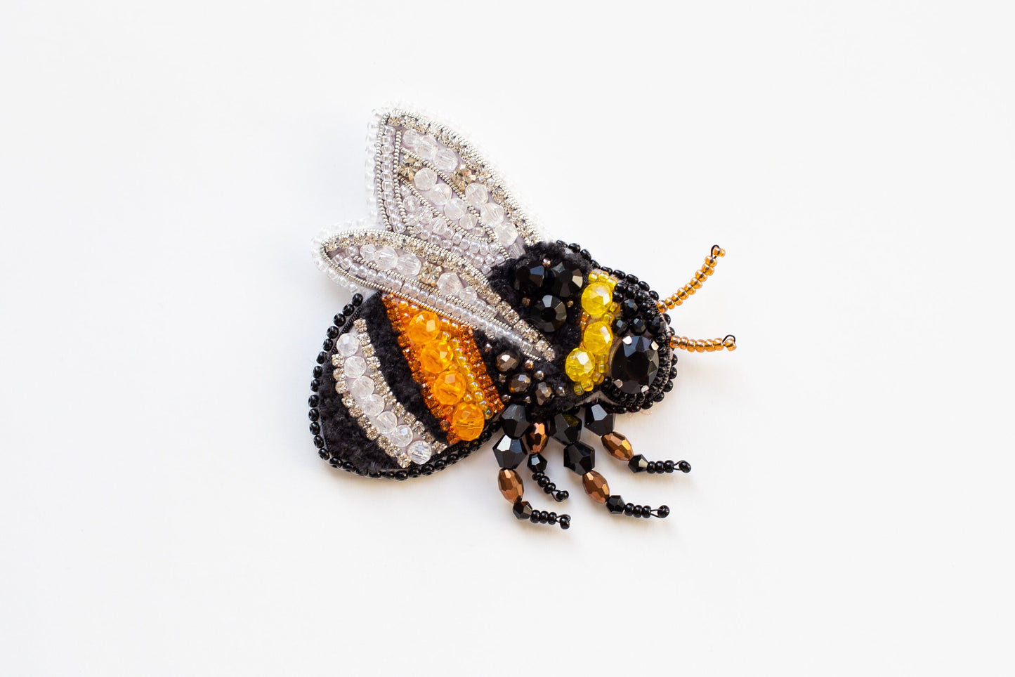 a beaded bee sitting on top of a white surface