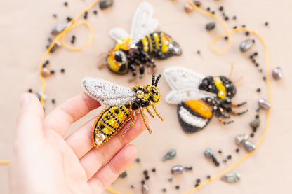 a hand is holding a tiny beaded bee