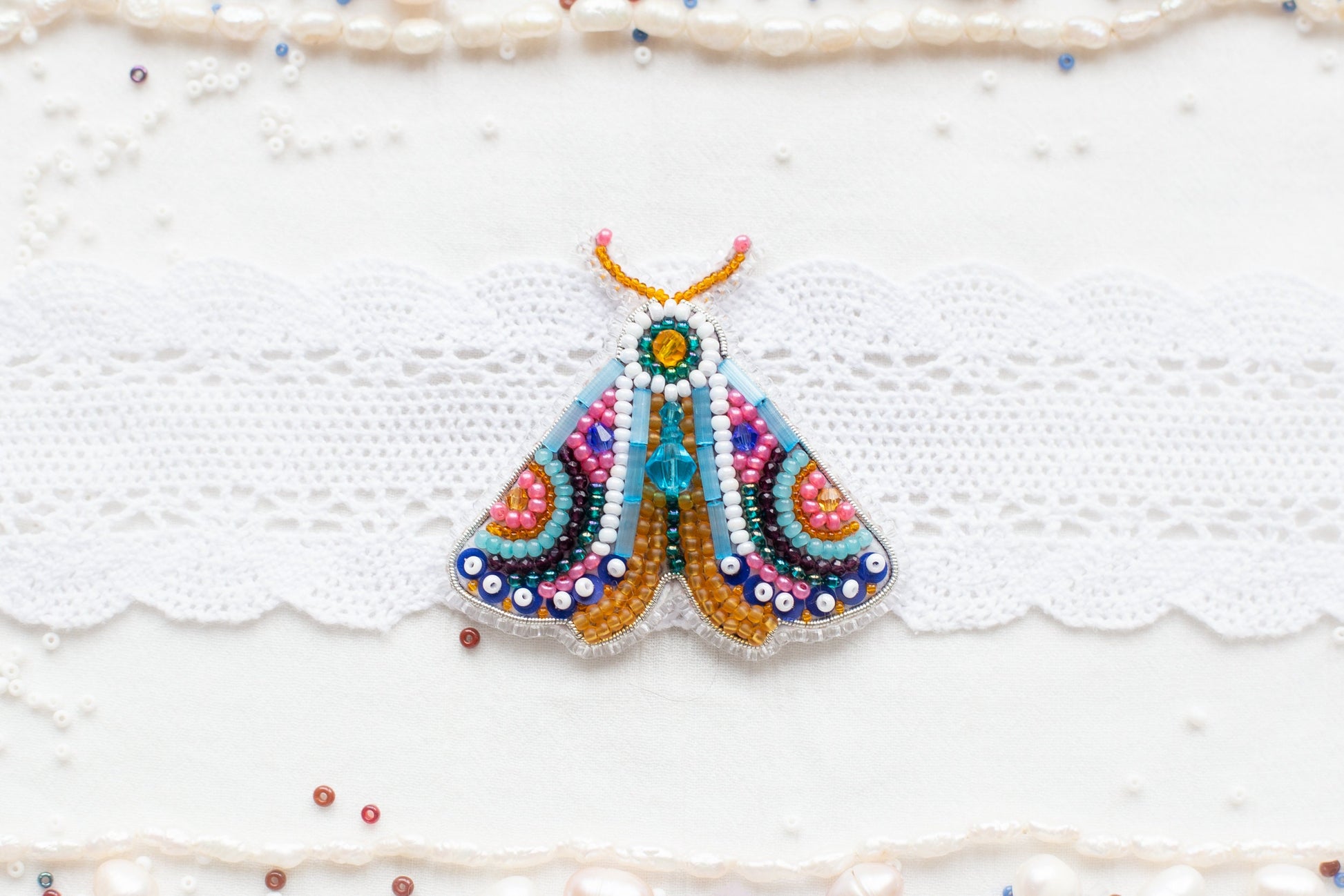 a colorful butterfly brooch sitting on top of a white lace