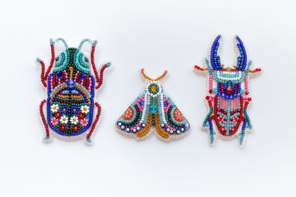 three beaded insect brooches on a white background