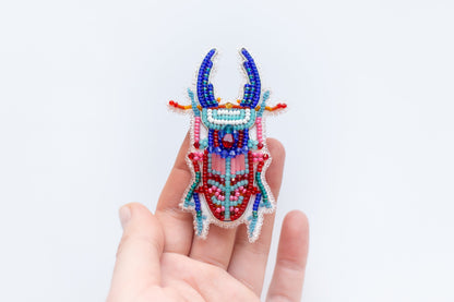 a hand holding a beaded animal brooch