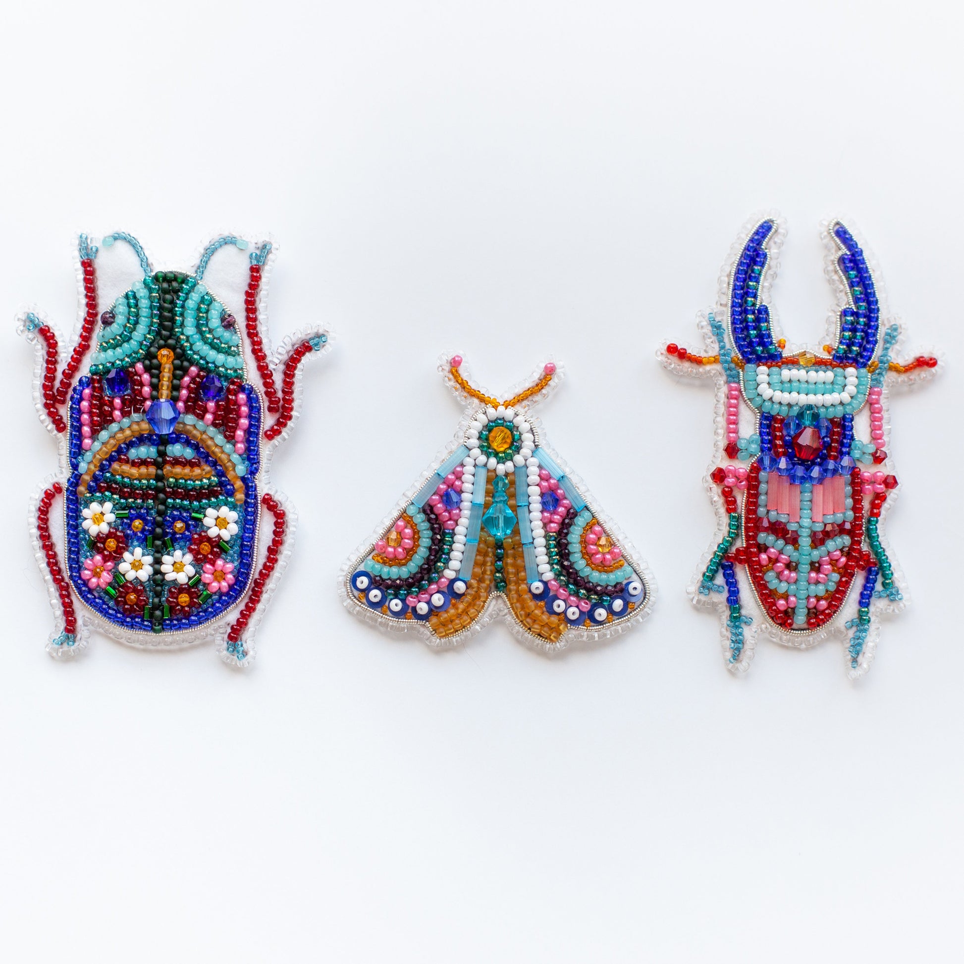 three beaded insect brooches on a white background