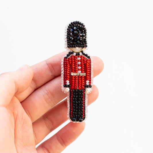 a hand holding a beaded nutcracker ornament