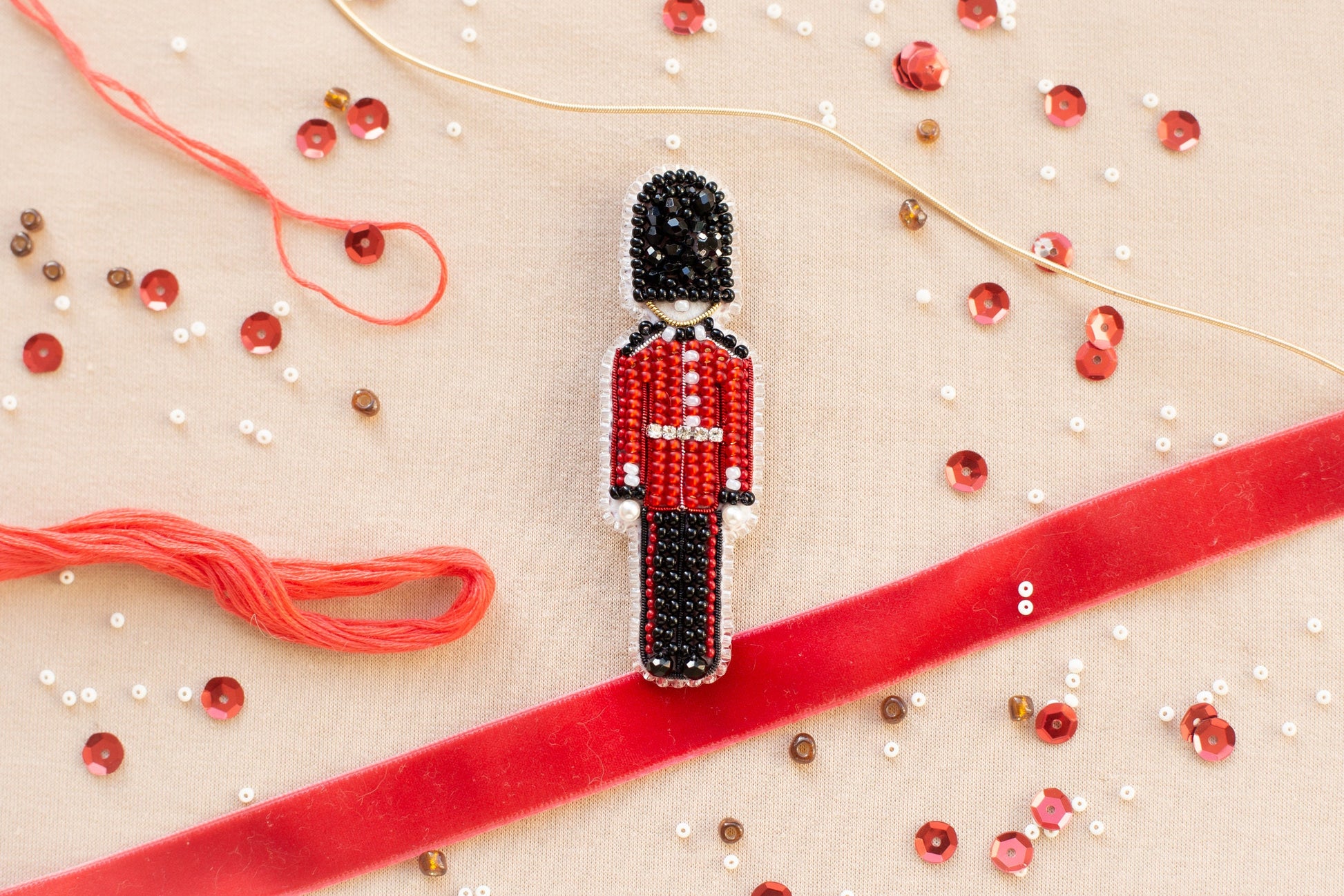 a beaded nutcracker ornament on a red ribbon