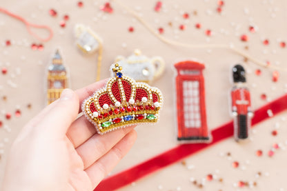 a hand is holding a beaded crown ornament