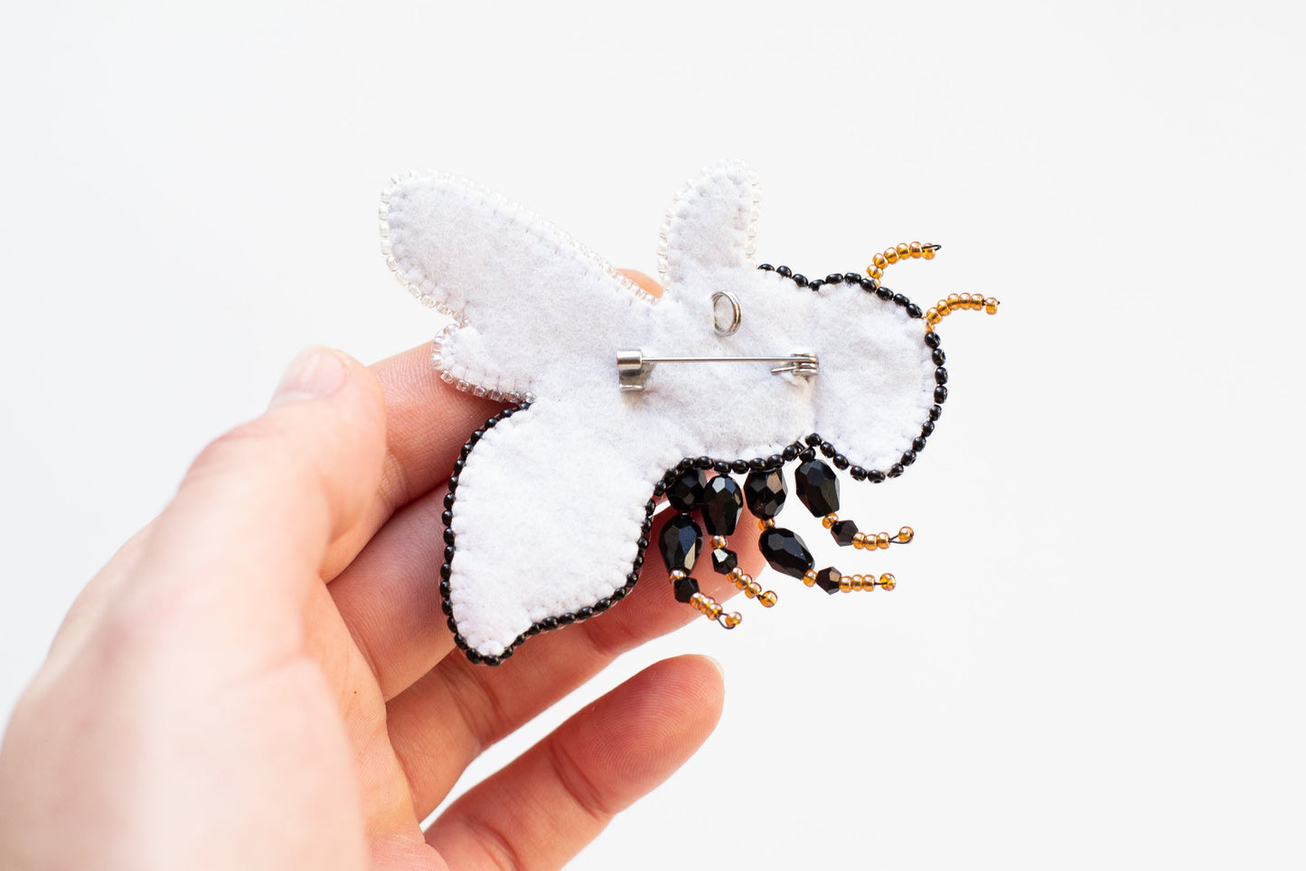 a person is holding a brooch with a bee on it