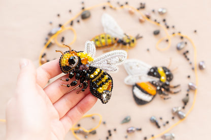 a hand is holding a tiny toy of two bees