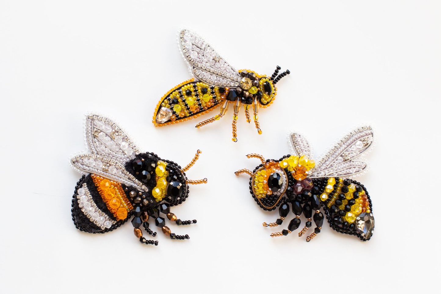 three beaded bees sitting next to each other on a white surface