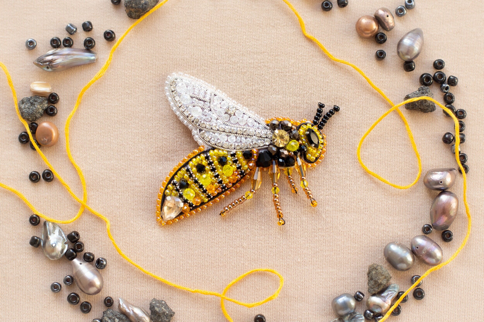 a beaded insect sitting on top of a yellow string