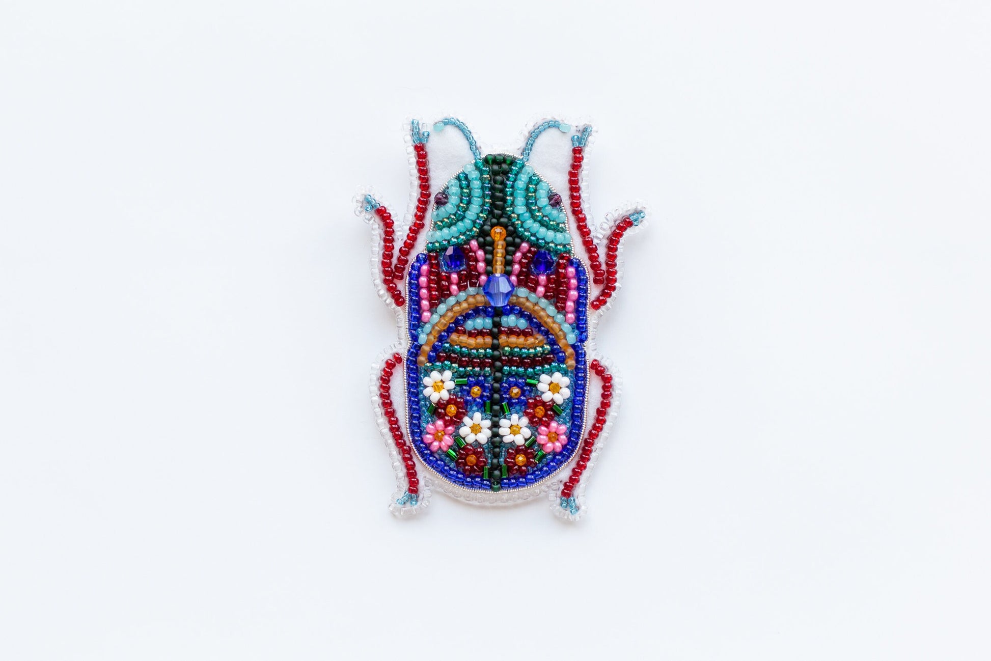 a beaded bug is sitting on a white surface