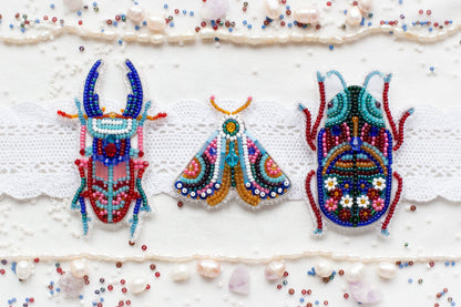 three beaded bugs on a white surface