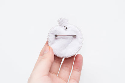 a person is holding a small white brooch