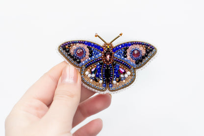 a hand holding a colorful butterfly brooch