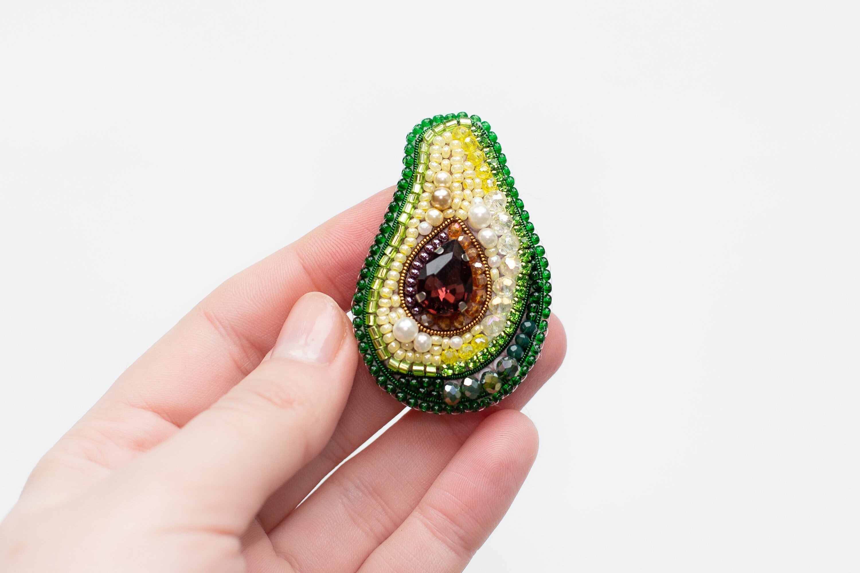 a person holding a beaded brooch in their hand