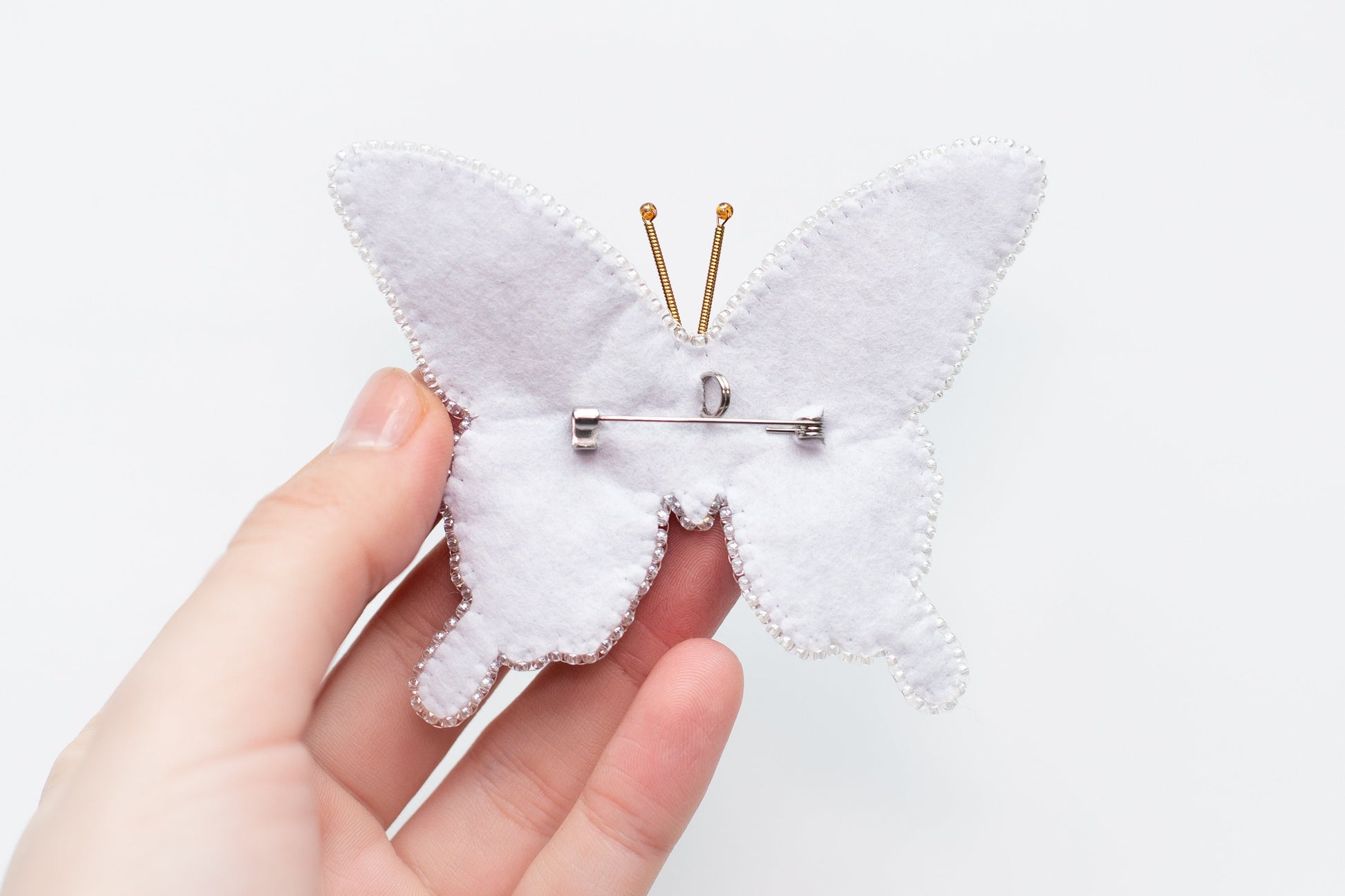 a person holding a pin with a white butterfly on it