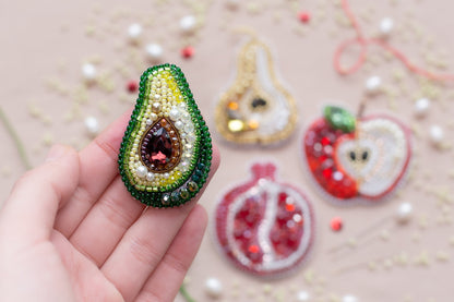 a hand holding a beaded fruit ornament