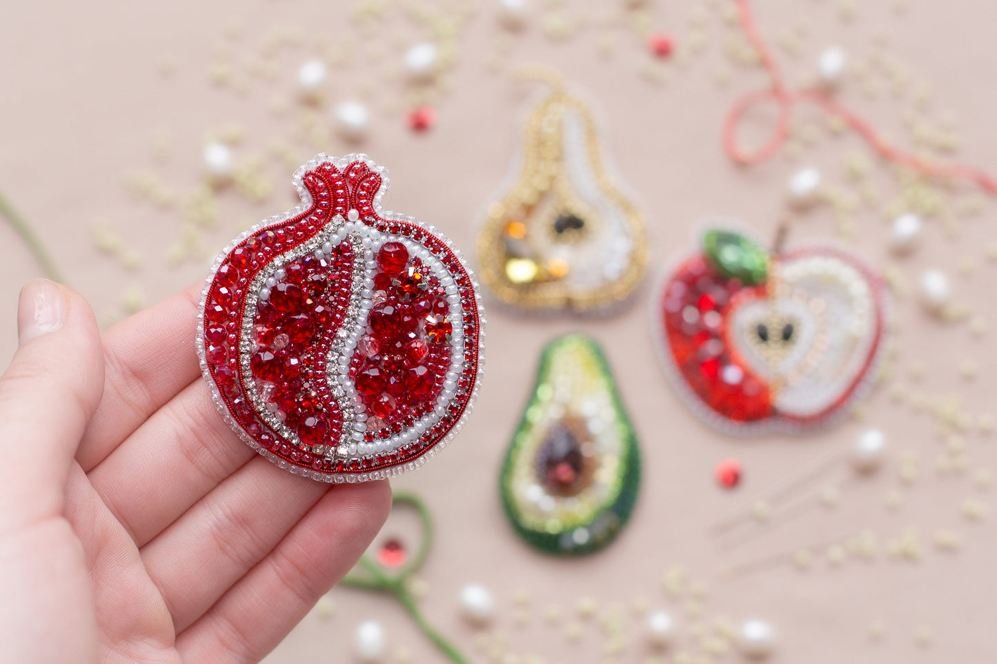 a hand holding a red ornament in front of other ornaments