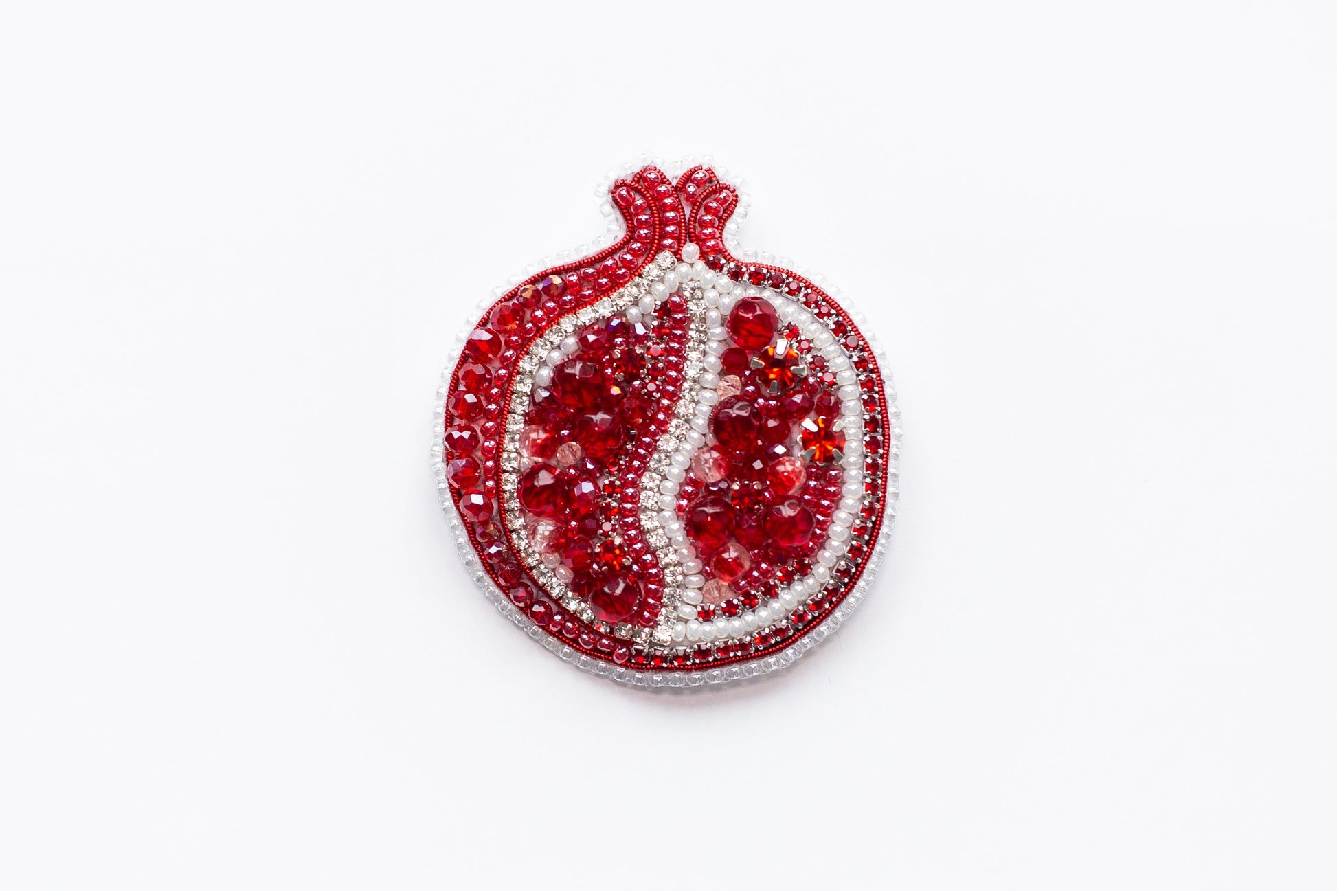 a red and white brooch sitting on top of a white surface