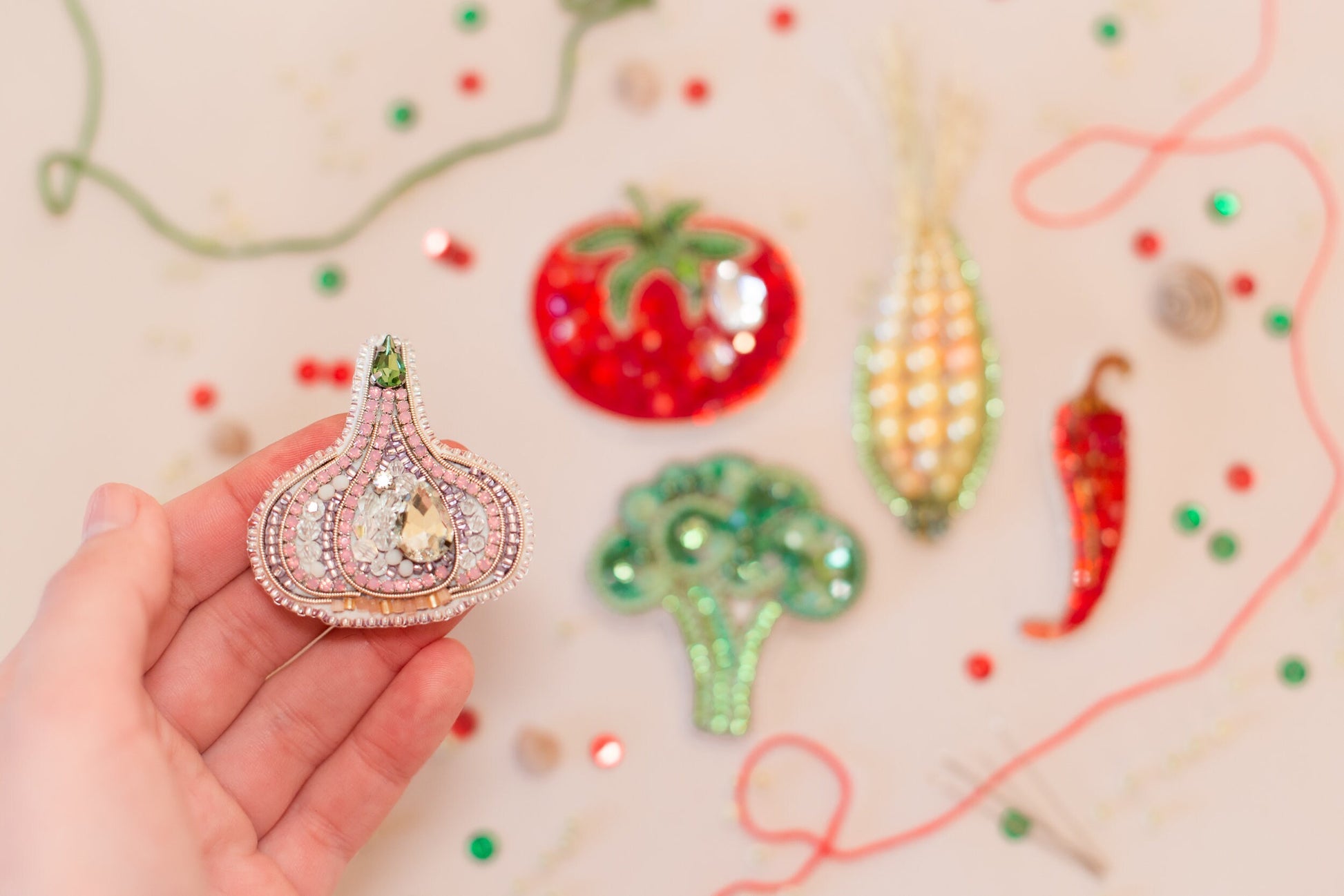 a hand is holding a brooch in front of a variety of brooches