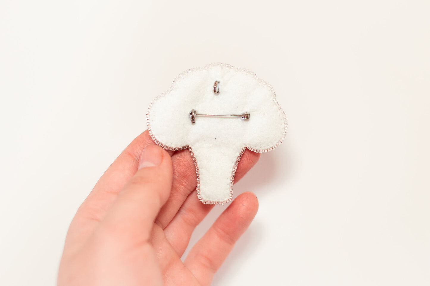 a person is holding a small white brooch