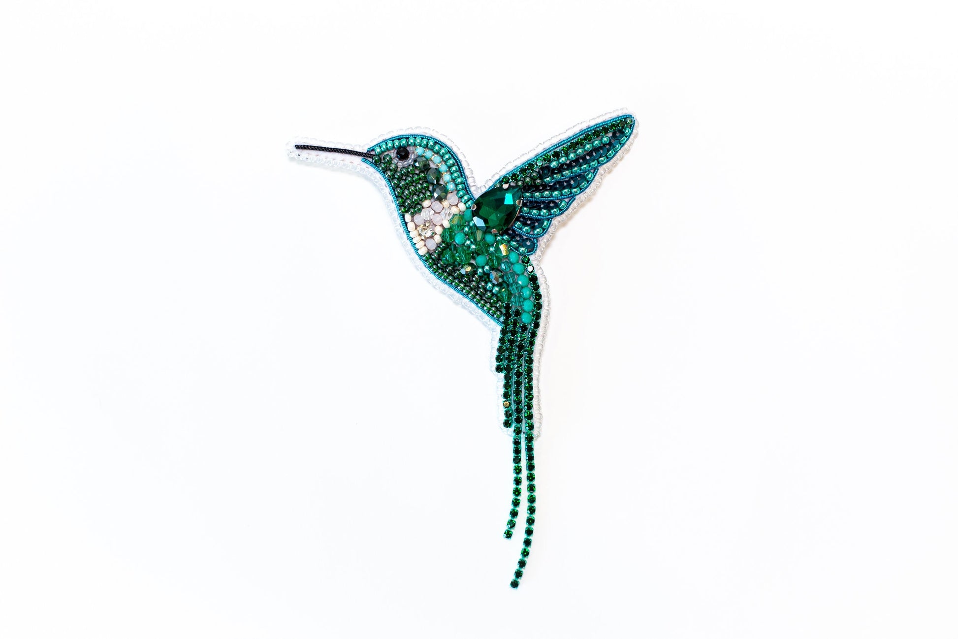 a beaded hummingbird brooch sitting on a white surface