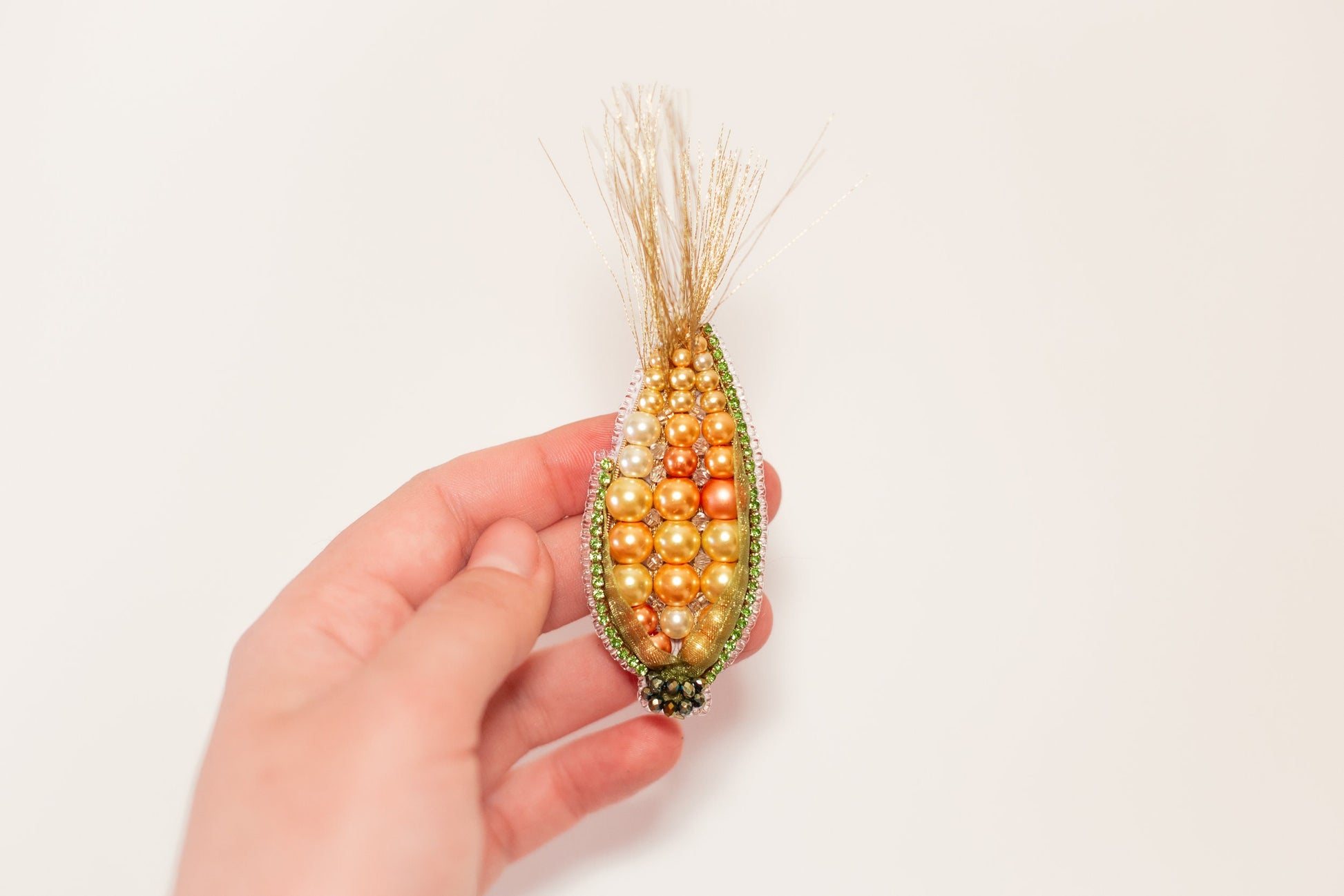 a hand holding a beaded corn on the cob