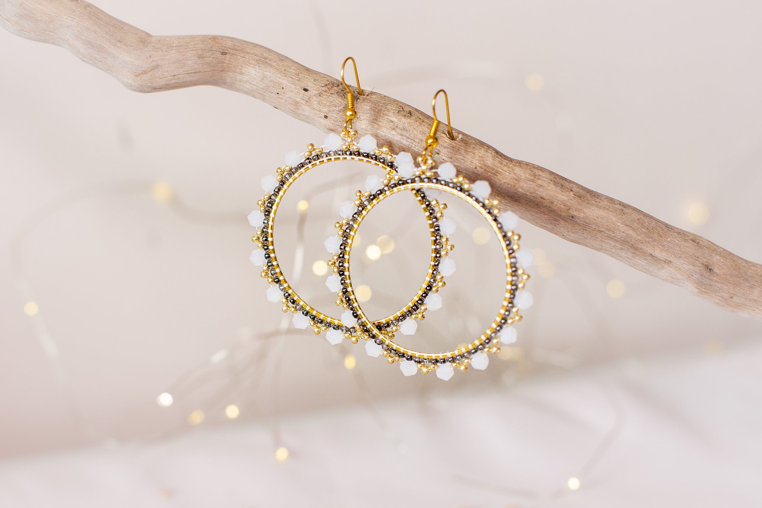 a pair of gold and white beaded hoop earrings