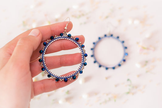 a hand holding a beaded bracelet and a pair of earrings