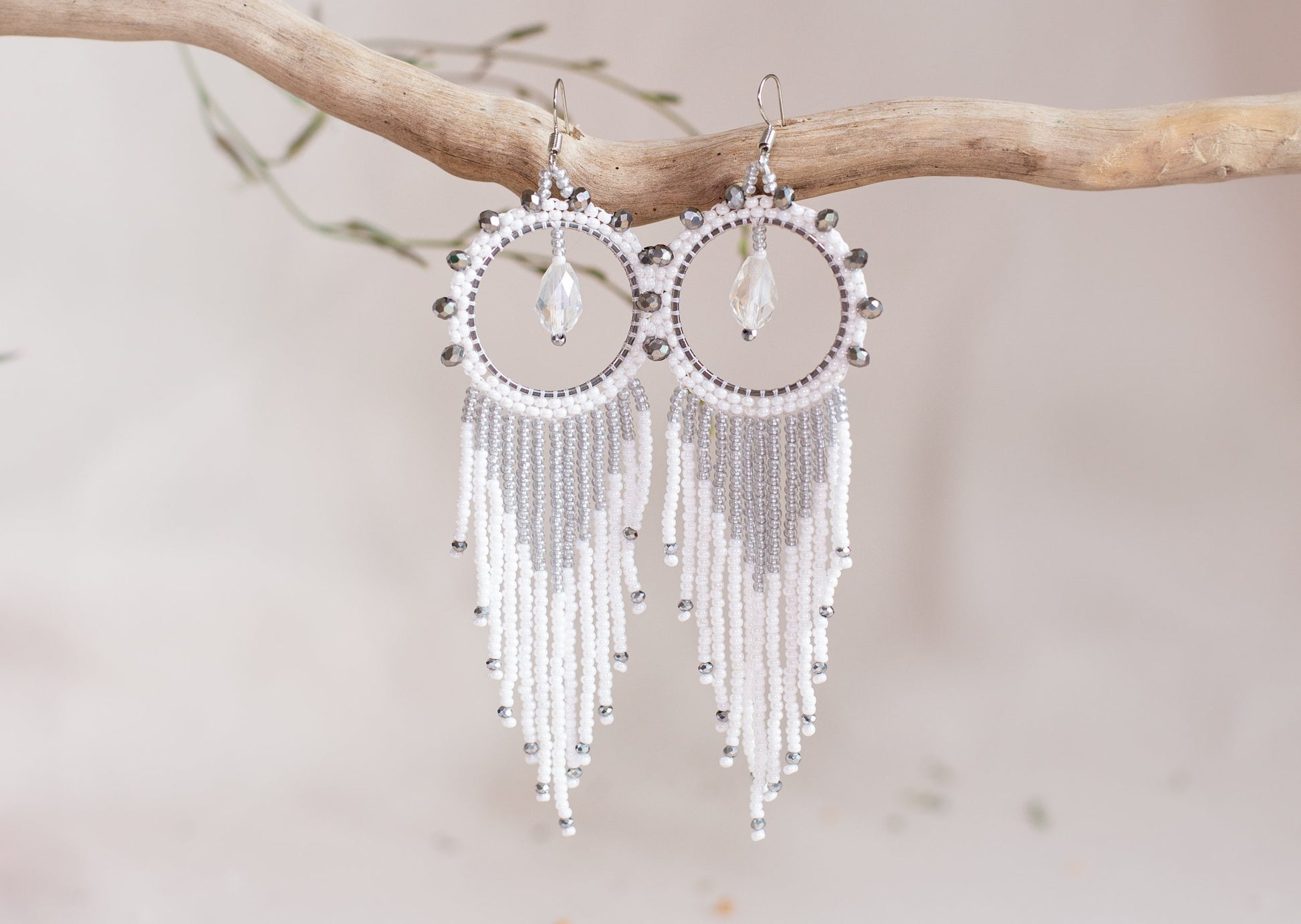 a pair of white beaded earrings on a pink background