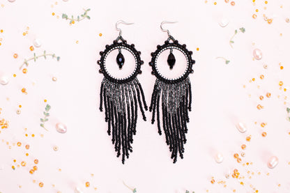 a pair of black beaded earrings with an evil eye