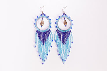 a hand holding a pair of blue beaded earrings