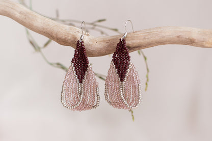 a pair of pink beaded earrings hanging from a branch