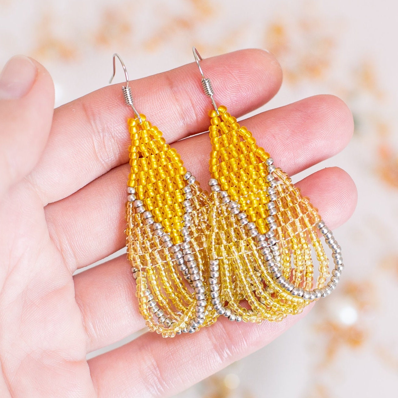 a pair of yellow beaded earrings sitting on top of a table