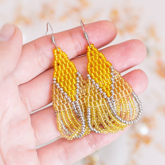 a pair of yellow beaded earrings sitting on top of a table