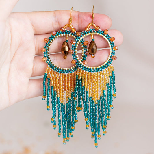 a pair of blue and yellow beaded earrings hanging from a branch