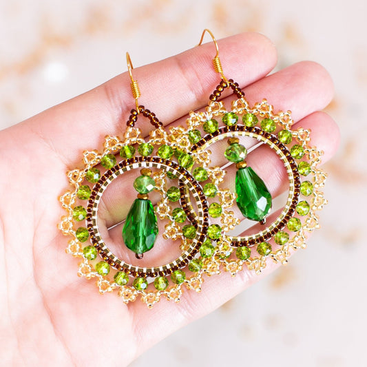 a pair of green earrings hanging from a tree branch