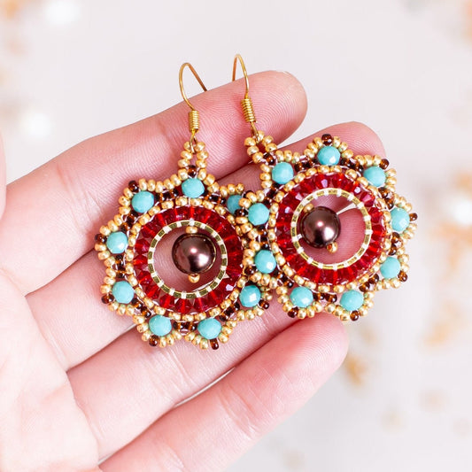 a pair of red, blue, and gold earrings on a branch