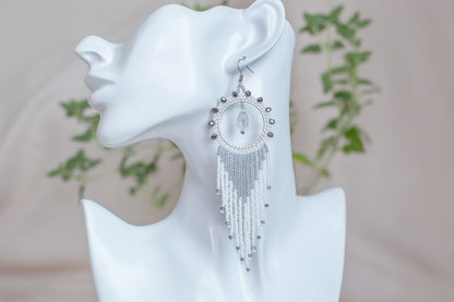 a white mannequin with a pair of earrings on it