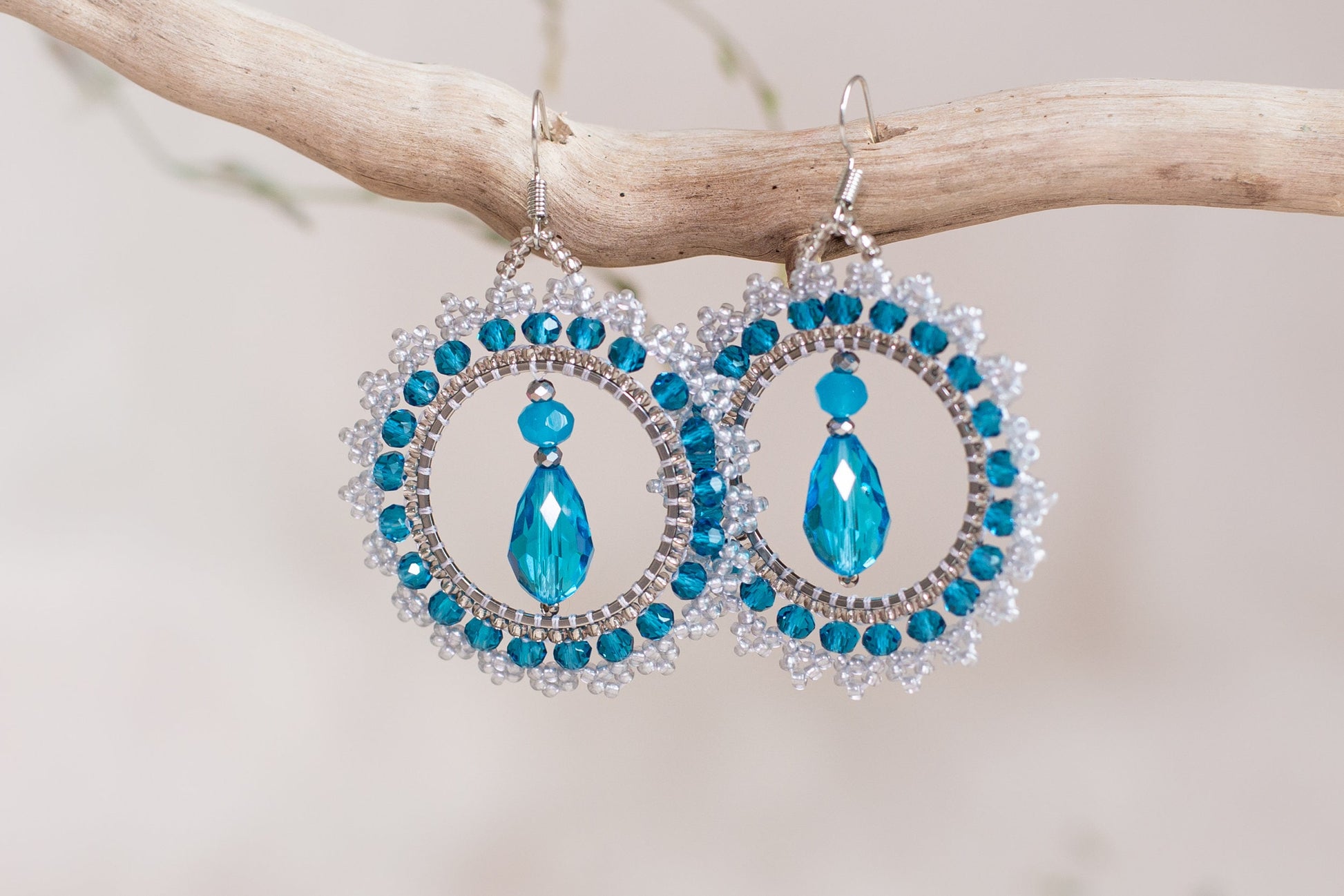 a pair of blue and white earrings hanging from a tree branch