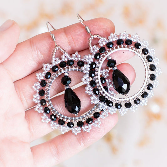 a pair of black and white earrings hanging from a branch