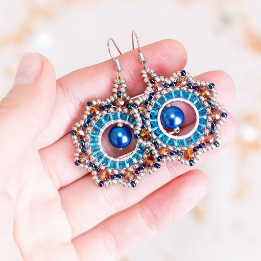 a pair of beaded earrings with a blue eye