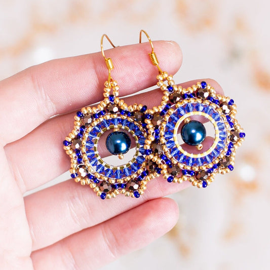 a pair of blue and gold earrings on a branch