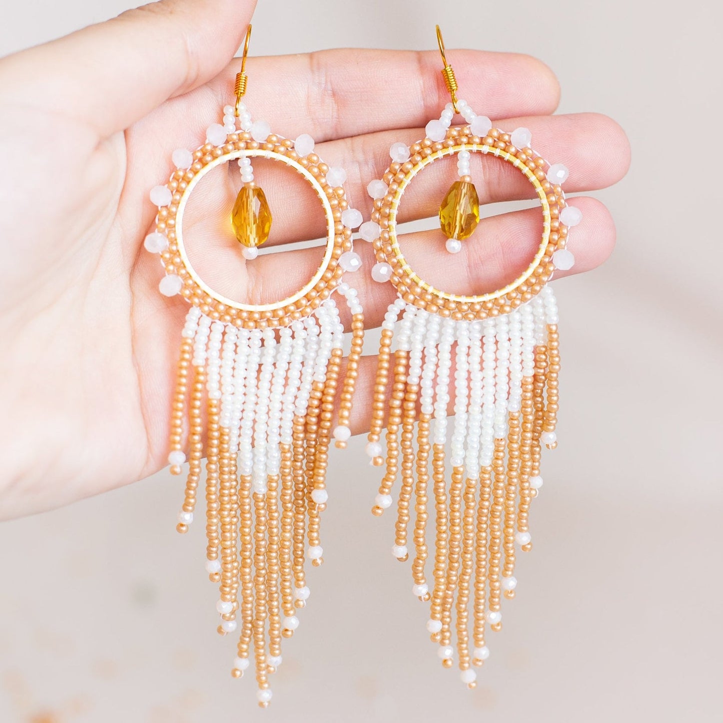 a pair of gold and white beaded earrings